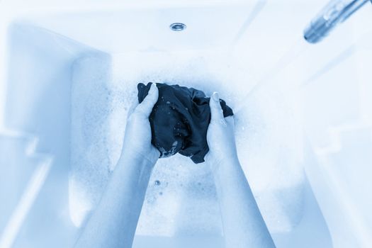 Female hands washing color clothes in basin