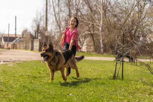 little girl running with his pet german shepherd.