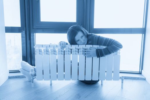 Woman wearing pullover sitting near heater radiator