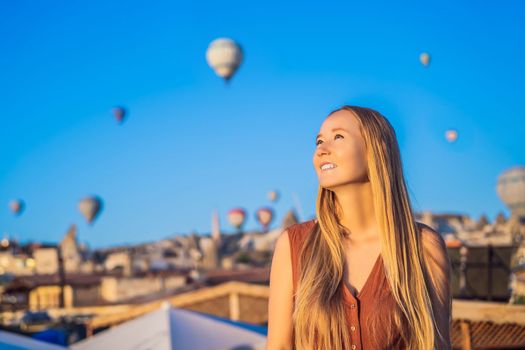 Tourist woman looking at hot air balloons in Cappadocia, Turkey. Happy Travel in Turkey concept. Woman on a mountain top enjoying wonderful view.