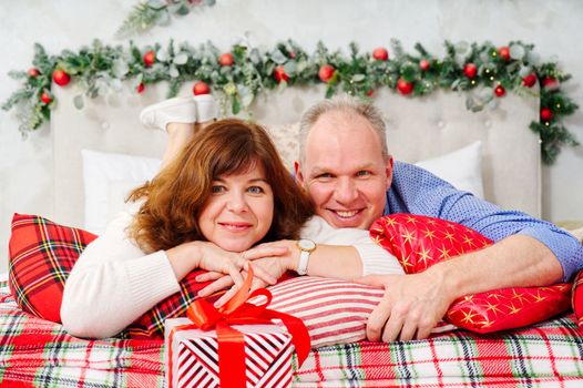 Passionate romantic couple spending time together. Christmas, New Year holidays at home concept. Cheerful couple lying cozy bed on Christmas morning and laughing.