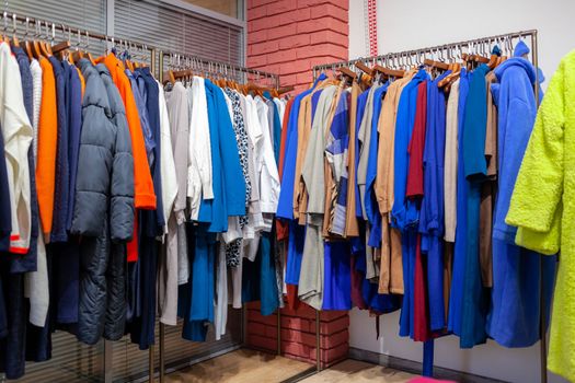 Colorful women's dresses, jackets, trousers and other clothes on hangers in a retail store. The concept of fashion and shopping. Women's clothing boutique.