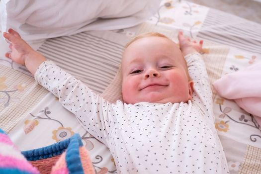 Cute little caucasian baby girl lying on the bed waling up in the morning