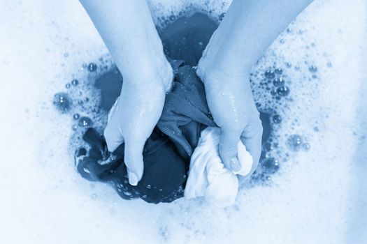 Female hands washing color clothes in basin