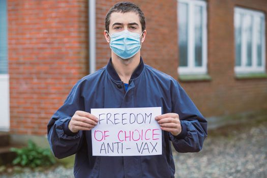 Man holding anti-vaccination poster near his house.