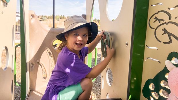 Little girl playing on modern children playground in the suburbs on a hot summer day.