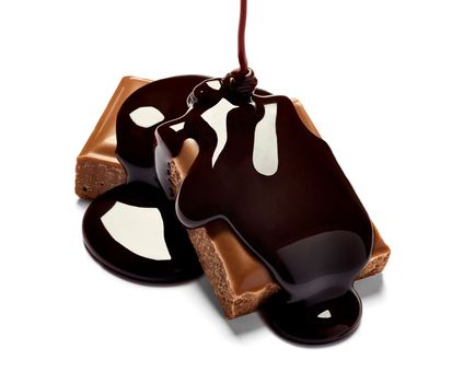 close up of chocolate pieces stack and chocolate syrup on white background