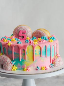 Close up of pink frosted dripping cake with donut and plastel brushed royal star sprinkles insolated on white studio shot