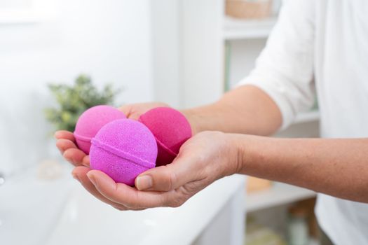 Closeup of a woman's hands with pink salt and soap balls in the bathroom for skin and body care. High quality photo