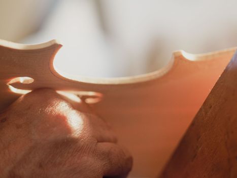 violin maker using a meter to shape and accurate measure fiddle scroll