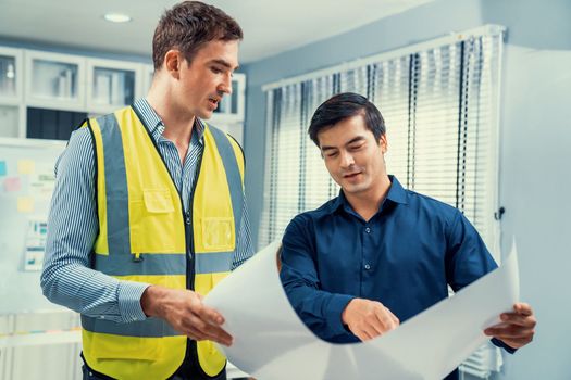 Competent investor investor discuss and brainstorm with engineer on blueprints, construction plans before putting them into action. Professional establishing investment plan for engineering projects.