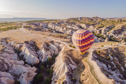 Colorful hot air balloons flying over at fairy chimneys valley in Nevsehir, Goreme, Cappadocia Turkey. Spectacular panoramic drone view of the underground city and ballooning tourism. High quality.