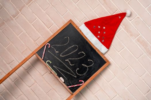 a black slate decorated with candy in the form of a caramel cane. The year 2023 is written in chalk on the blackboard. Happy New Year. 2023. Number written in chalk on a school board