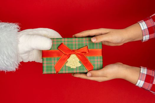 Santa's hands give gifts to children at Christmas. red background with copy space Christmas time