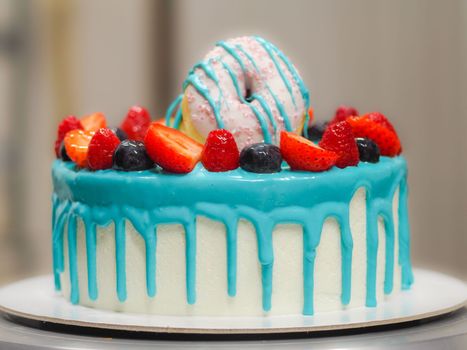pastry chef cake designer decorating turquoise blue white frosted cheesecake in kitchen with piping bag