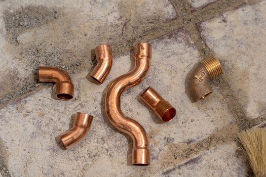 Copper fittings close-up on the concrete floor. Soldering of water distribution pipelines in the apartment. High quality photo