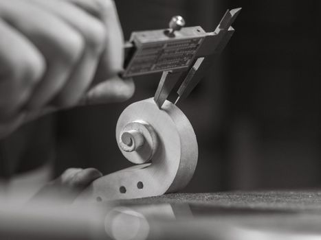 violin maker using a meter to shape and accurate measure fiddle scroll