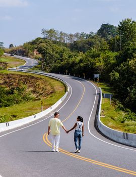 A couple walking on a curved road in the mountains of Nan Thailand, Road nr 3country road rear view. Number three road among the mountains, a couple man and women on vacation in Nan Thailand.