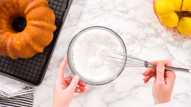 Flat lay. Step by step. Mixing ingredients in a glass mixing bowl to prepare lemon glaze for a lemon bundt cake.