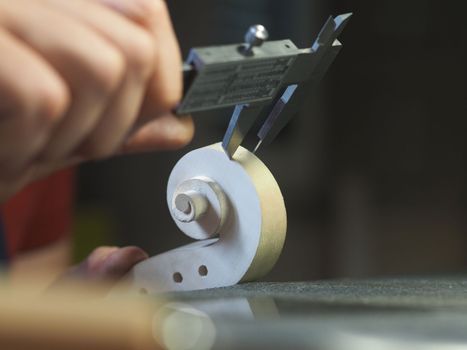 violin maker using a meter to shape and accurate measure fiddle scroll