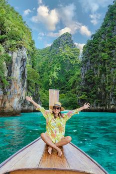 Asian women with hands up in front of a longtail boat at Kho Phi Phi Thailand, women in front of a boat at Pileh Lagoon