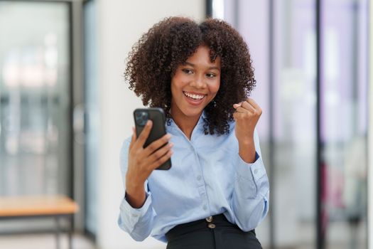 Business black woman having phone conversation with client in office. African american young woman using smart phone.