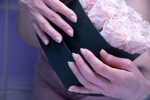 pink wedding manicure for the bride, a girls hand on the black heart shape box. High quality photo