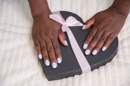 hands of black girls with beautiful blue manicure on the black heart, High quality photo