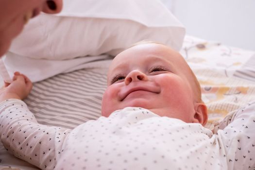 Cute little caucasian baby girl lying on the bed waling up in the morning