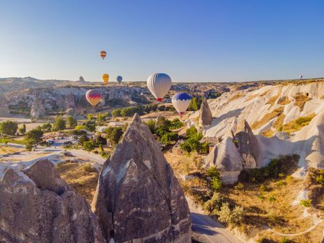 Colorful hot air balloons flying over at fairy chimneys valley in Nevsehir, Goreme, Cappadocia Turkey. Spectacular panoramic drone view of the underground city and ballooning tourism. High quality.