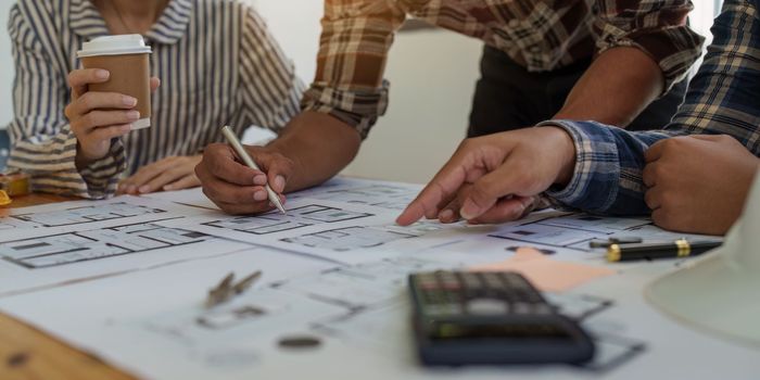 Professional architect designer structural engineer team colleagues discussing building plan design project.