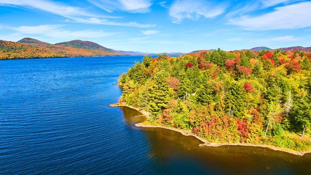 Image of Aerial over lake with fall tree forest covering coast and blue waters
