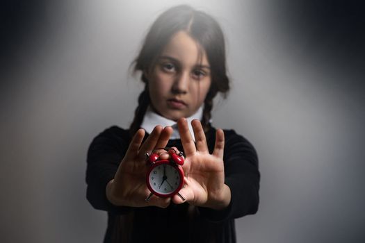 Wednesday Gothic girl with alarm clock. High quality photo