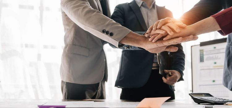 Group of business people putting their hands working together on wooden background in office. group support teamwork agreement concept