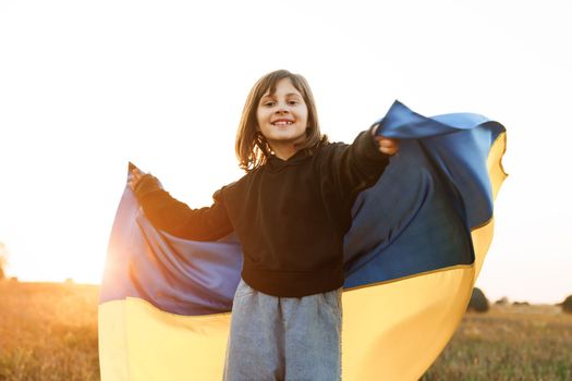 Portrait of Ukrainian child girl in embroidered shirt vyshyvanka with yellow and blue flag of Ukraine in field. Ukraines Independence Flag Day. Constitution day. Flag symbols of Ukraine. Kiev day