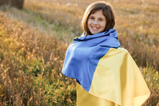 Portrait of little girl in traditional embroidery with flag of Ukraine. Woman holding a yellow and blue flag of Ukraine in outdoors. Independence Day. Flag Day. Constitution day.