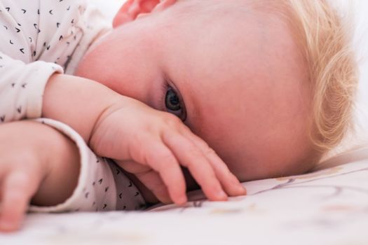 Cute little caucasian baby girl lying on the bed waling up in the morning