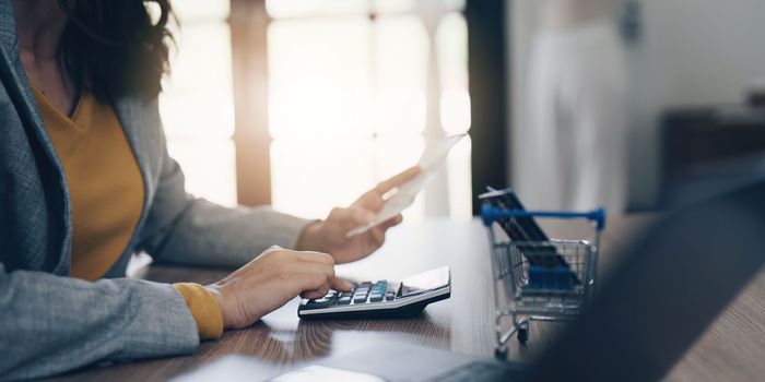 Young Asian Woman checking bills, bank account balance, taxes and calculating expenses at home.