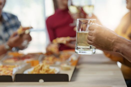 Friends at birthday party clinking glasses with champagne and pizza, enjoying Christmas vacation, pizza on the table. Holiday Party event