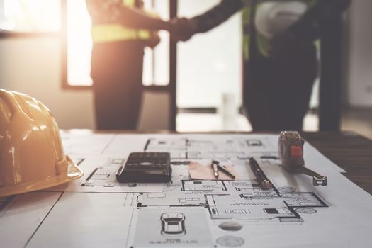 Architect and engineer construction workers shaking hands after finish an agreement in the office construction site, success collaboration concept.