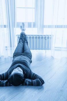 Woman laying on floor with feet raised up on radiator for warming