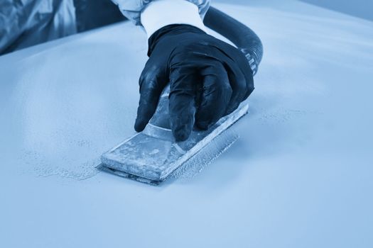 Auto mechanic buffing and polishing car in auto repair shop