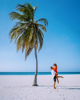 Eagle Beach Aruba, Palm Trees on the shoreline of Eagle Beach in Aruba, a couple of man, and woman on the beach of Aruba