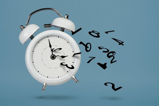 Time is running out. White alarm clock with flying numbers as a symbol of lost time. The concept of time is running out, loss or lack of time, an alarm clock with numbers shatters into small pieces