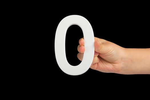 Zero in hand. The number zero is clasped in a hand isolated on a black background. Number zero white in a child's hand on a black background