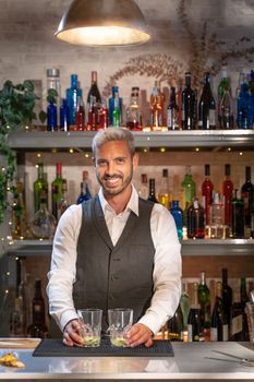 Elegant barman smiling on bar counter. High quality photo