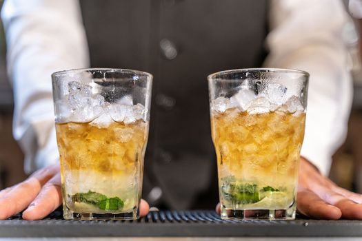 Barman serves Mojito in night club adding ingredients and creating expert drinks on bar counter. High quality photo