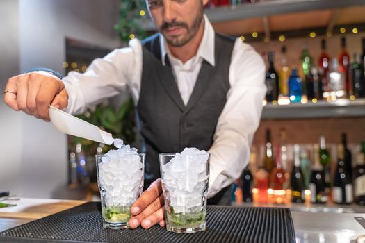 Barman making cocktail Mojito in night club adding ingredients and creating expert drinks on bar counter. High quality photo