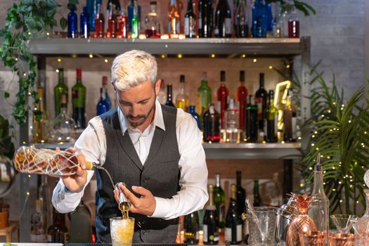 Barman making cocktail Mojito in night club adding ingredients and creating expert drinks on bar counter. High quality photo