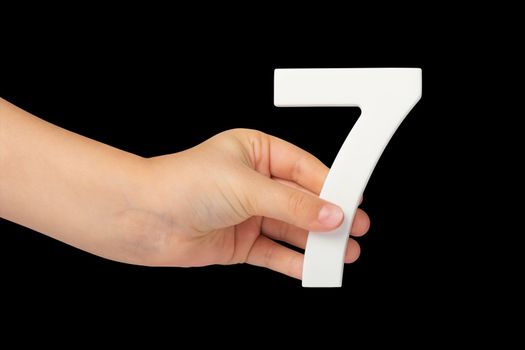 Number seven in hand isolated on black background. Number 7 in a child's hand on a black background. To be inserted into a project or design